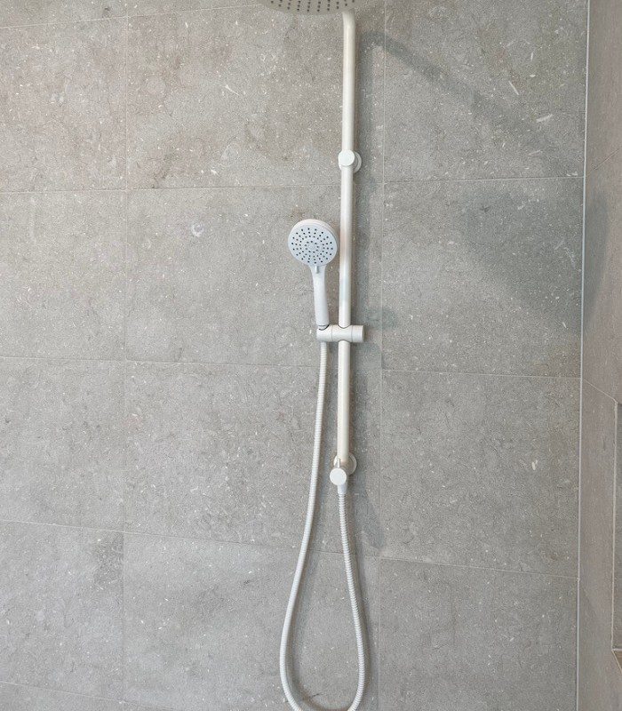 While often used for floors, Sage limestone makes the perfect versatile natural stone bathroom tile. It’s used to tile the wall behind a white wall-mounted shower head. Neutral light-coloured grout ties in the complex sage colouring.