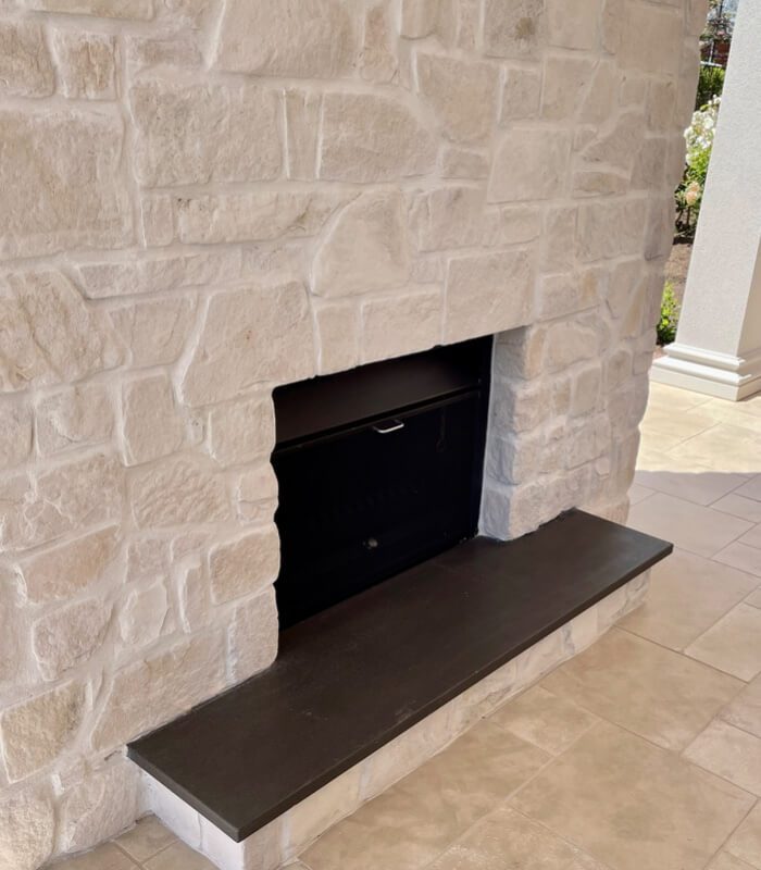 A creamy random ashlar stone fireplace featuring dark wooden accents.