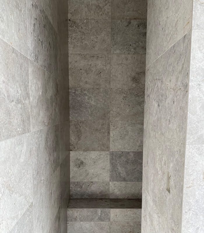 Tundra Grey Limestone tiles installed as walling in a shower and on a bench.