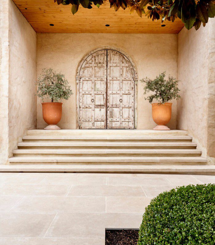 Osmond Limestone laid as outdoor stairs at Bird in Hand winery in Woodside, South Australia. There’s an ancient looking door and two terracotta pots containing olive trees.