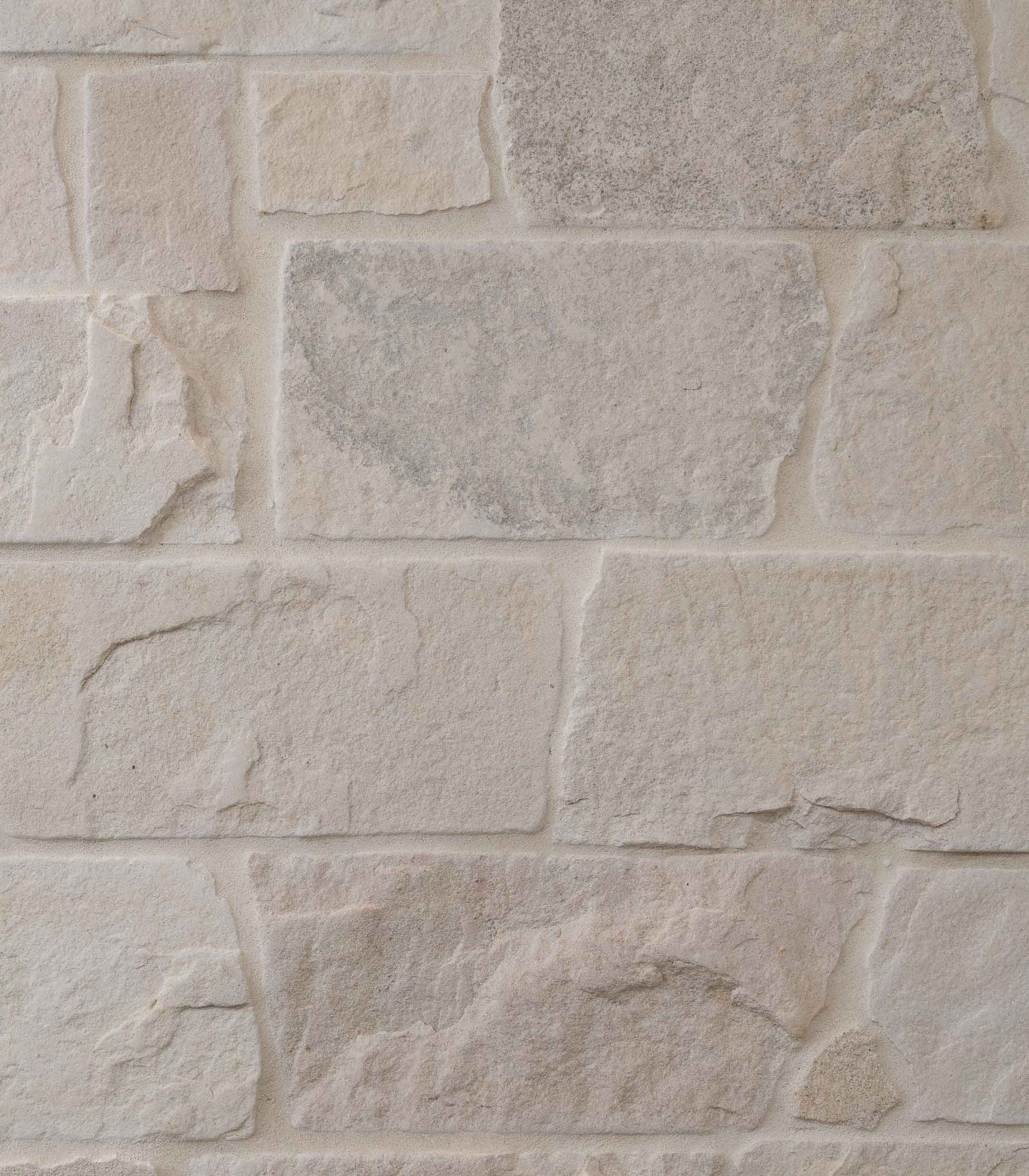 Cream-toned tumbled sandstone wall with tonal grouting.