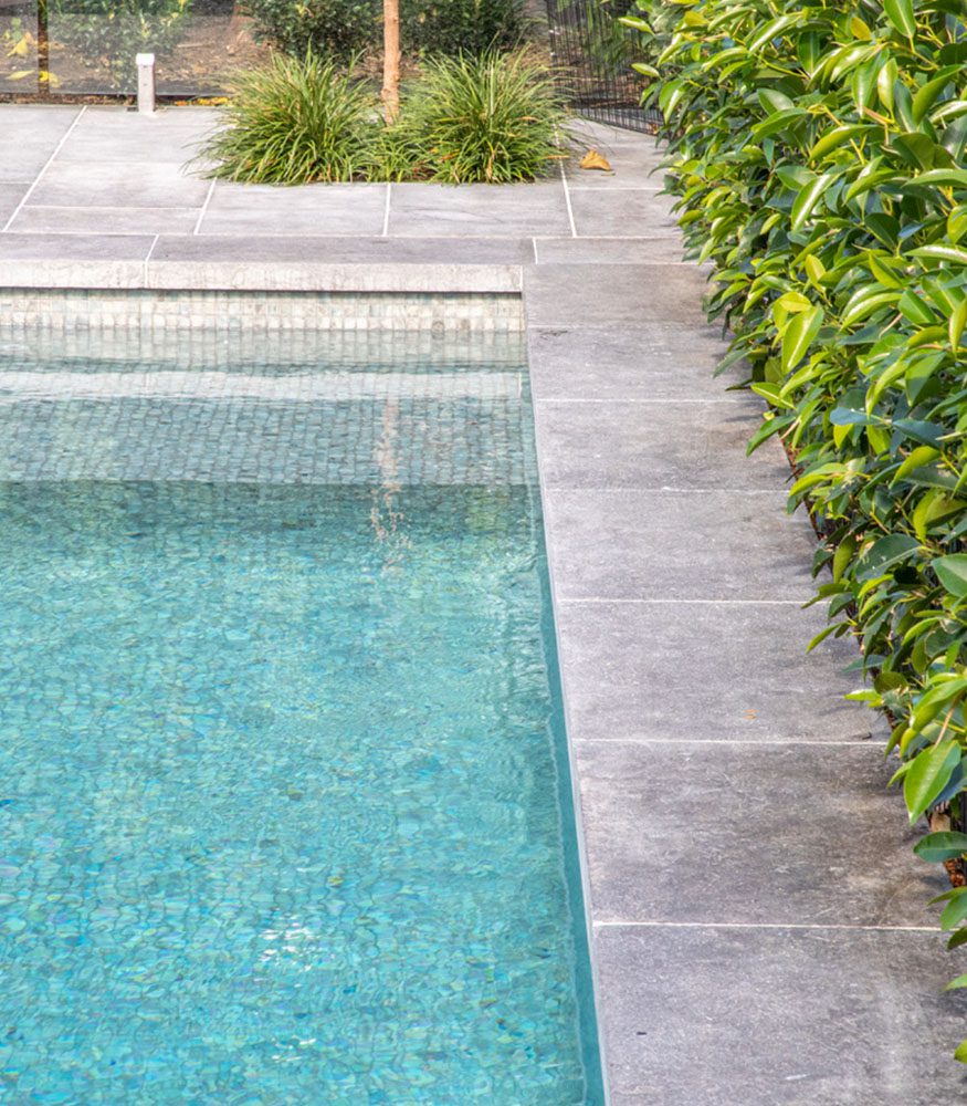 A swimming pool surrounded by Tumbled’s Ava Limestone, a natural grey paver.