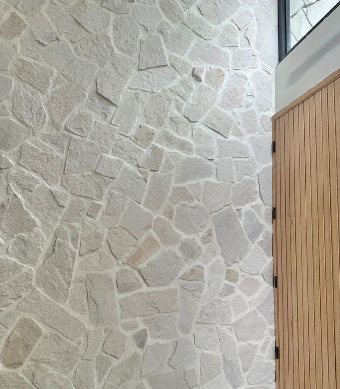 Wooden gate fixed to a stone feature wall. The stone is Beau Irregular sandstone, a cream and grey-coloured stone with a light tonal grout.
