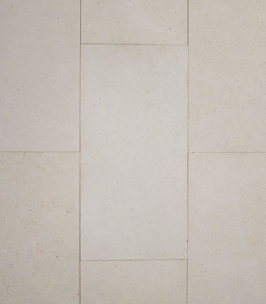A close-up image of Tumbled Brulee Limestone with sawn edges. The textured stone's colour is light and creamy with specks of caramel.