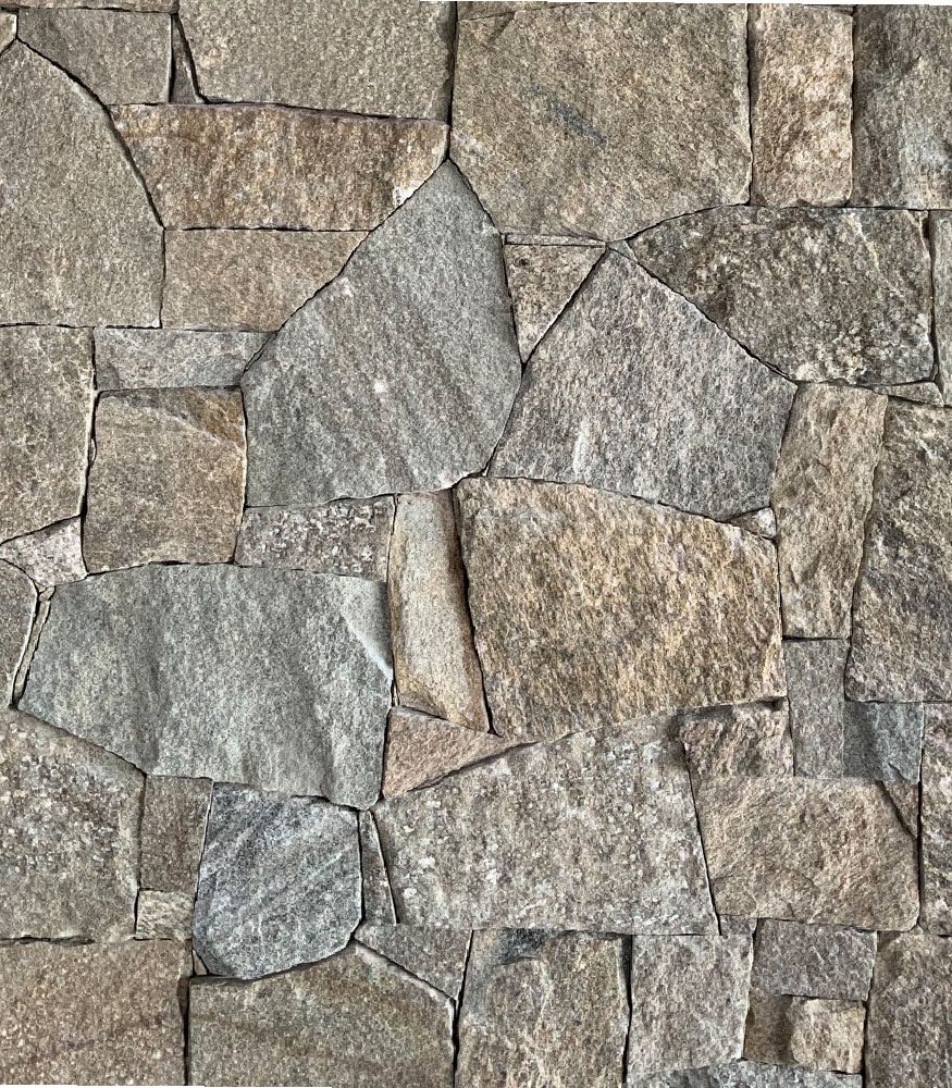 An image showcasing Chalet Irregular walling. Chunky stones of all shapes are placed together to create a wall. The stones are a mixture of grey, brown and burnt orange with specs of dusty white throughout.