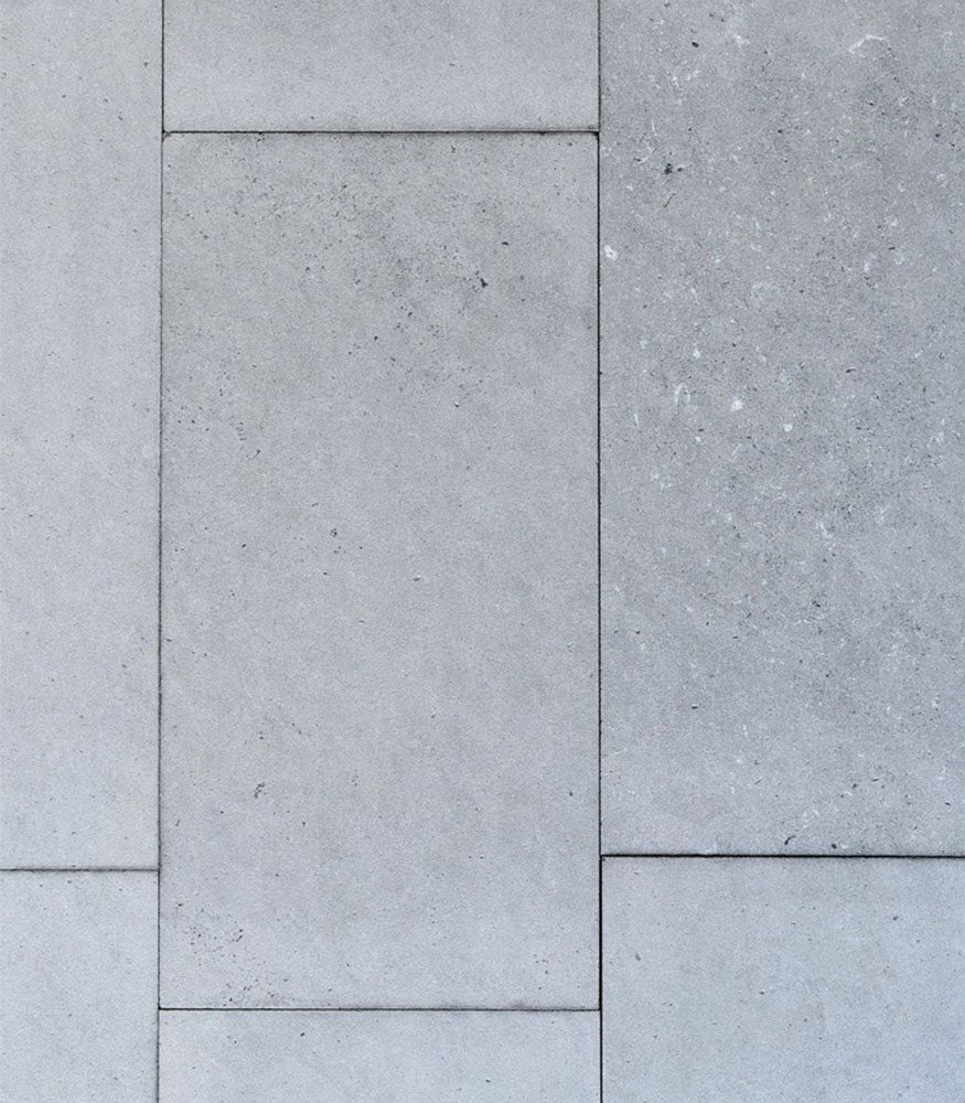 Tumbled Mia Limestone in a horizontal stacked pattern. The stone tiles are grey in colour and feature white specs and a rough texture.