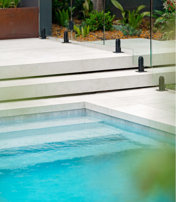 Olivia Limestone pool tiles and steps surrounding a blue pool.