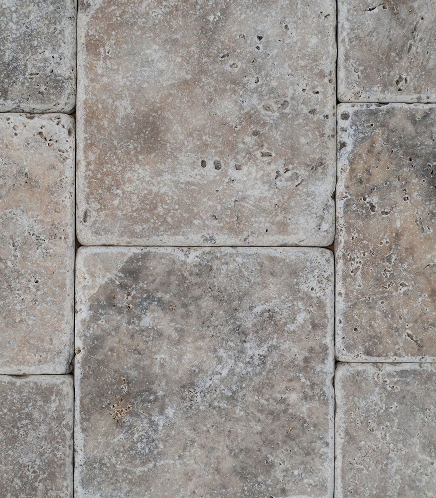 Close up image of Silver travertine tiles without grout; each piece showcasing natural variations in texture and tone.