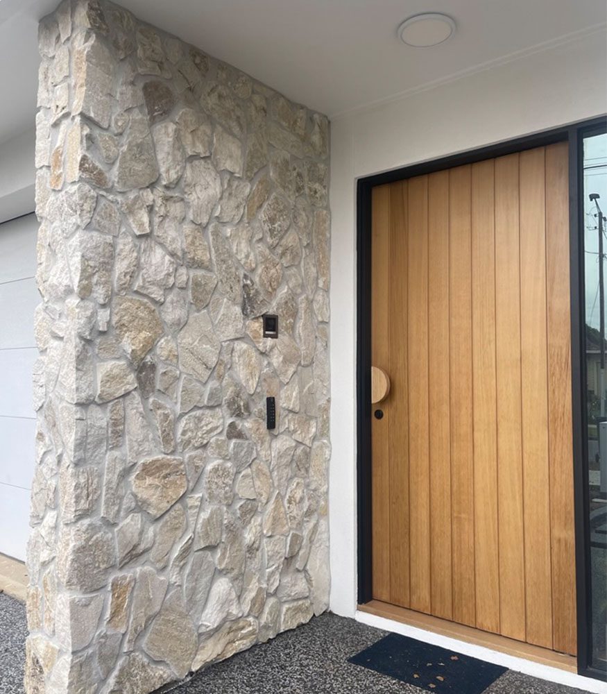 Somerton Irregular stone cladding is used as a feature facade next to a home’s wooden front door. The stone wall has tonal grouting.