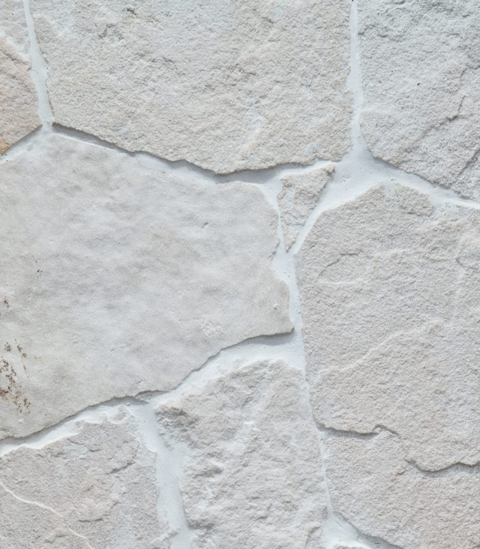 A close up image of creamy Tumbled sandstone walling with tonal grout.